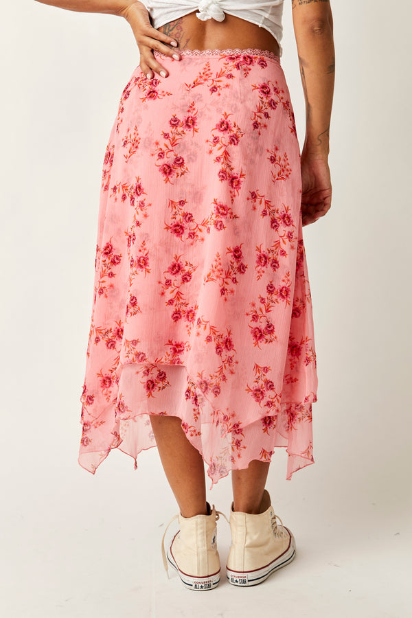 back view of model wearing the garden party skirt in pink blossom. shows the lace, scalloped lace trim at the waist. also shows the asymmetrical hem and the beautiful vintage floral print. 