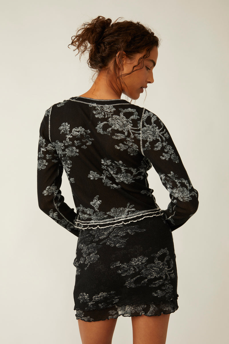 back view of the model wearing the garner tee in black. shows the lettuce style trim detail. also shows the defined seaming throughout and the fitted style.