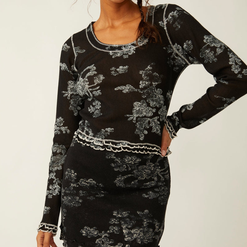 front view of the garner tee in black. shows the lettuce style trim detail. also shows the scoop neckline, the defined seaming throughout and the beautiful floral print.