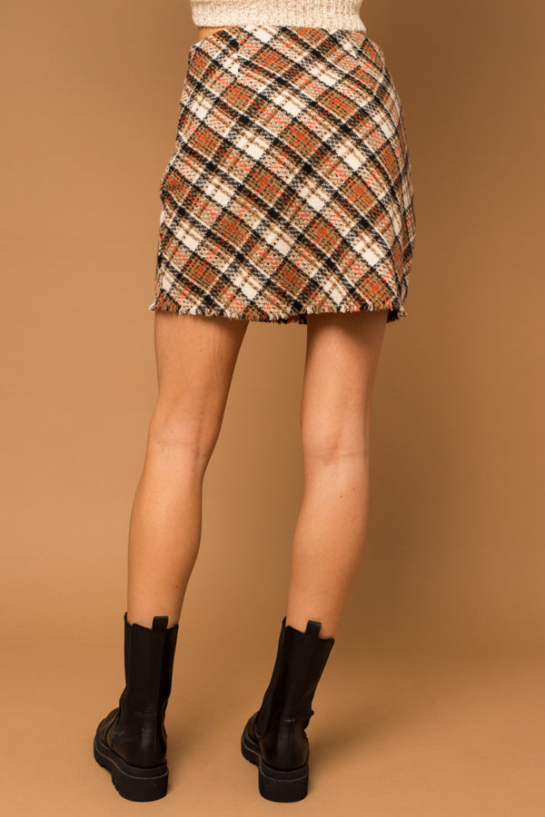 Back view of model wearing skirt. Shows the frayed bottom hem. Also shows the two pleats by the waist. 
