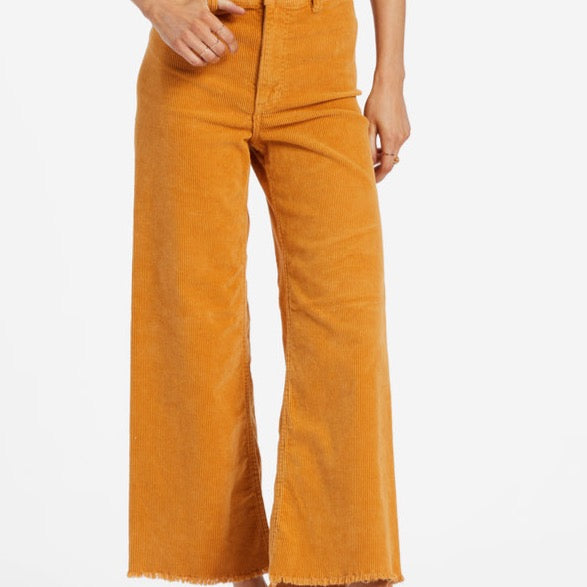 front view of the free fall pants in golden rays. shows the frayed raw hem. also shows the button and zip closure, the wide leg and some of the belt loops.