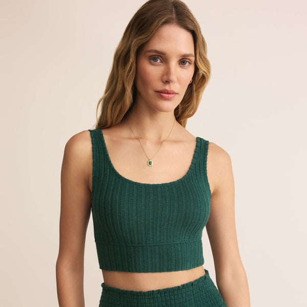 Woman wearing a green ribbed crop top and pants on a beige background