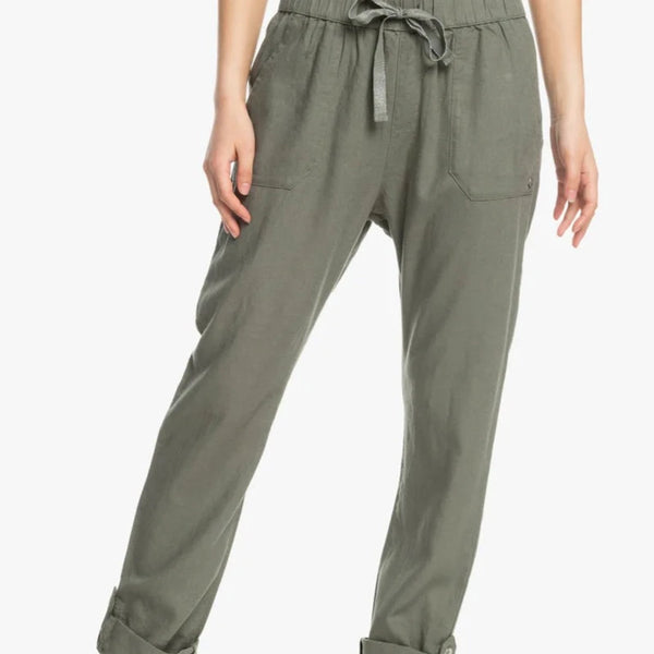 front view of the model wearing the on the shore cargo pants in agave green. shows the drawcord closure. also shows the synched waist, the front pockets and the rollable bottom cuffs.  