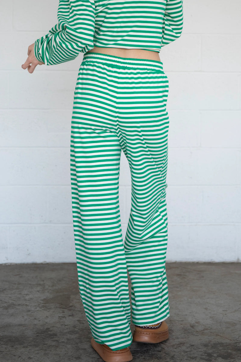 back view of the model wearing the frankie pants. shows the elastic waistband. also shows the wide legs, the green and white stripes and pull on style. 