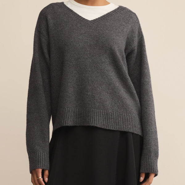 Woman wearing a gray sweater with a white collar against a beige background
