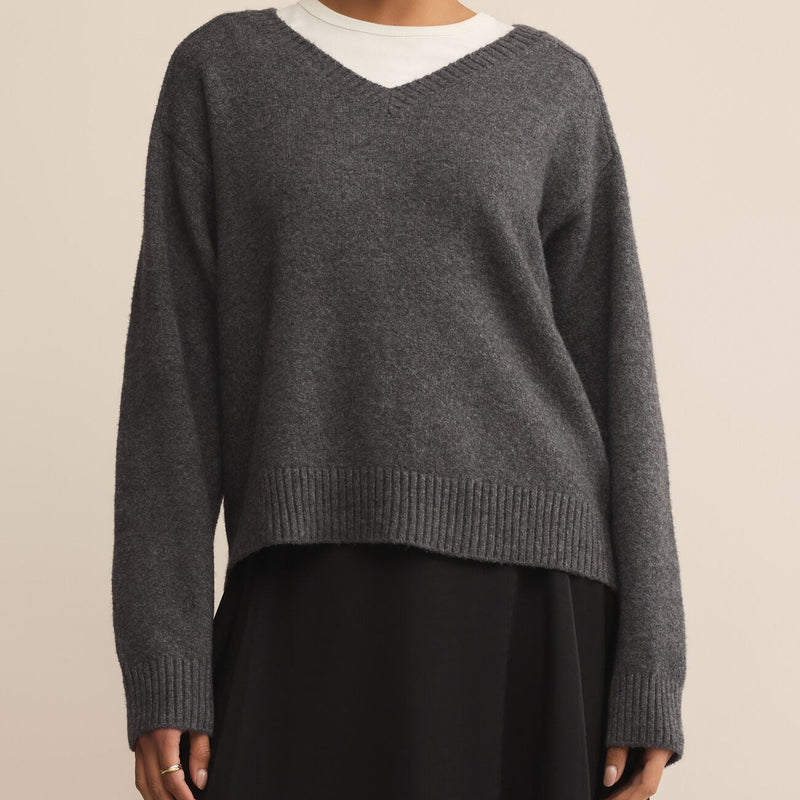 Woman wearing a gray sweater with a white collar against a beige background