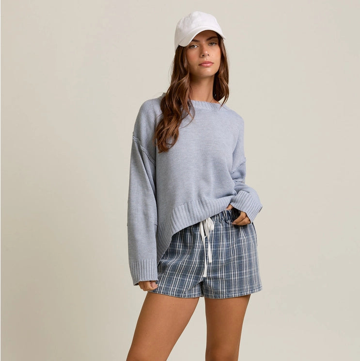 front view of the model wearing the rosy sweater top. shows the round neckline. also shows the dropped shoulders, the heather grey color, the hi low style and the ribbed detailing. 