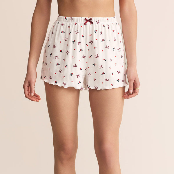 White pajama shorts with a floral pattern worn by a person on a beige background