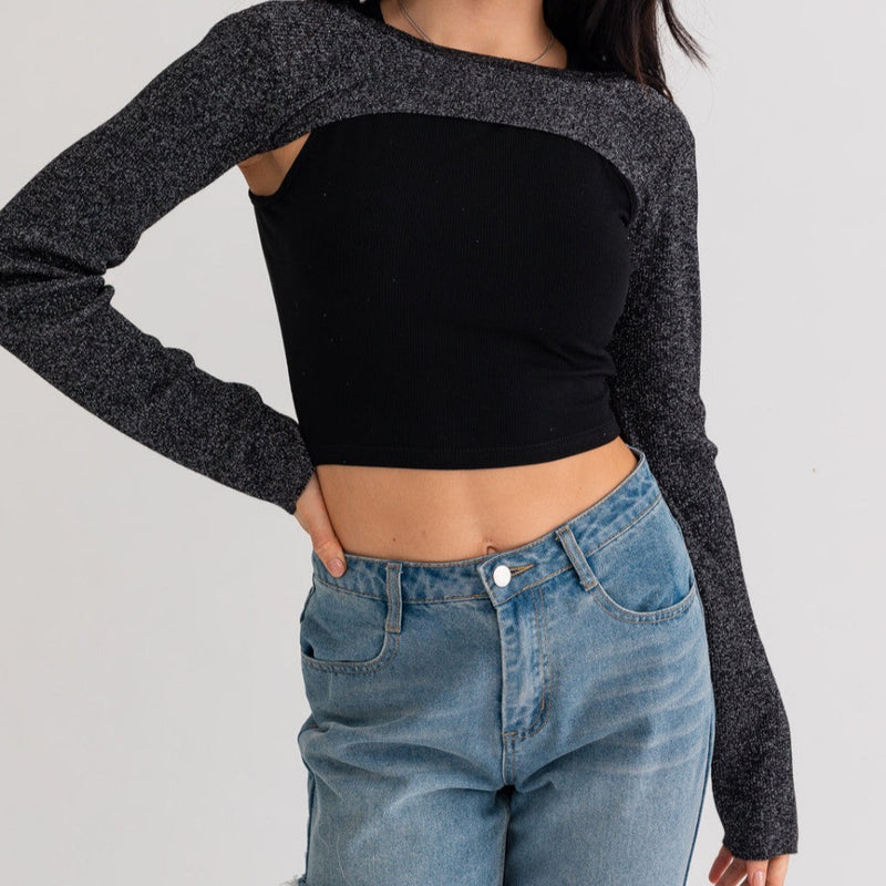 Front view of model in sweater rug and ribbed tank top. Shows the cropped ribbed tank top in black. Also shows the black and metallic srug that is long sleeve. The srug is high neck and covers arms and shoulders.