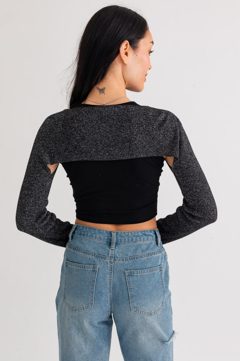 Back view of model wearing sweater srug and ribbed tank top. Shows the back of the black cropped ribbed tank top. Also shows the black and metallic srug that is covering models shoulders and arms. Srug is long sleeves. 