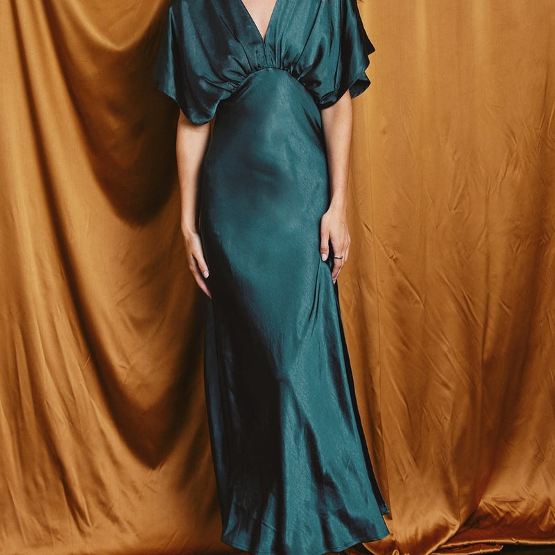 front view of the model wearing the Mallory maxi dress in deep jasper. shows the v neckline. also shows the blouson top, the short sleeves and the maxi length. 