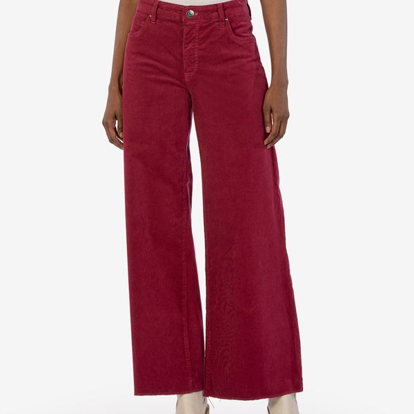 Front view of model wearing pants. Shows the button closure and front pockets. Also shows the wide leg, bottom raw hem and the beautiful color ruby. 