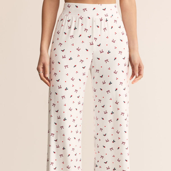 White pajama pants with a subtle pattern worn by a person on a beige background