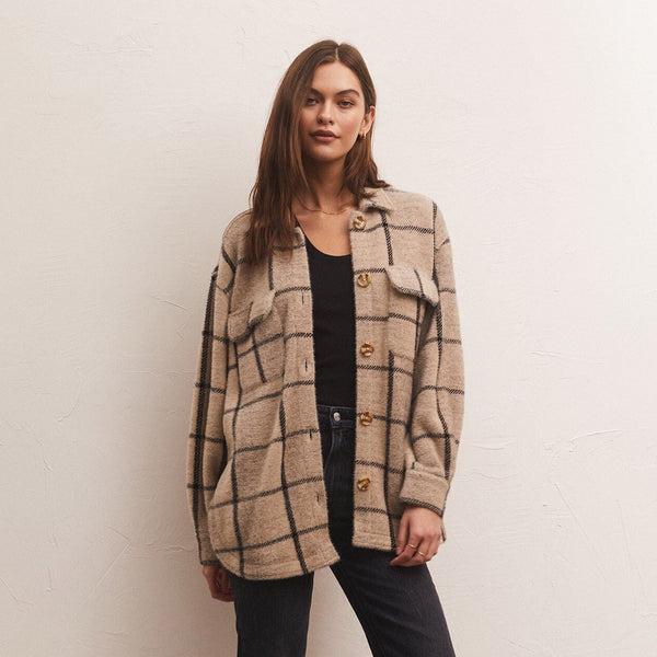 front view of model in jacket. shows the plaid design, front pouch pockets with flaps and brown buttons down the center. hits model at top of thigh.