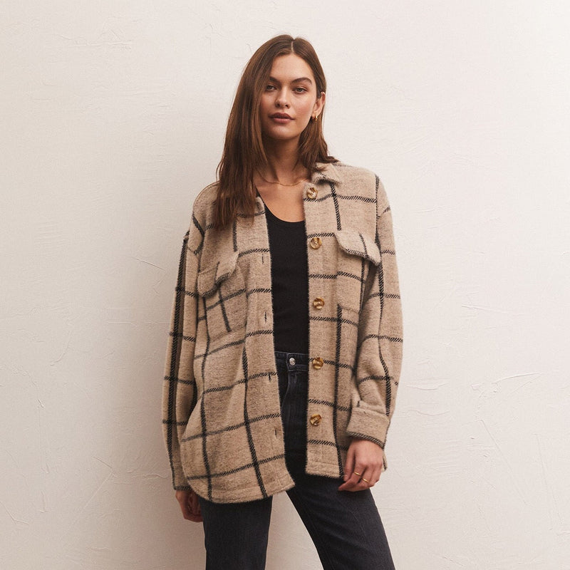 front view of model in jacket. shows the plaid design, front pouch pockets with flaps and brown buttons down the center. hits model at top of thigh.