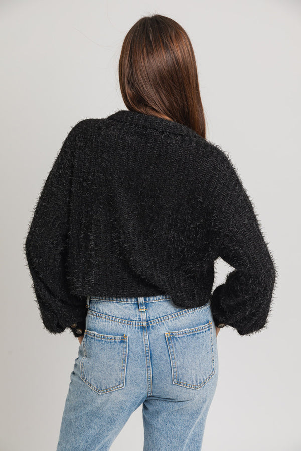 back view of model wearing the chloe cropped shacket in black. shows the cropped length. also shows the oversized sleeves and the collar. 