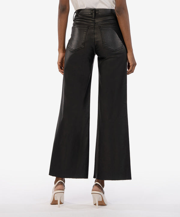 Back view of model wearing pants. Shows the back butt pockets. Also shows the bely loops, the wide legs, the coating and the black color. 