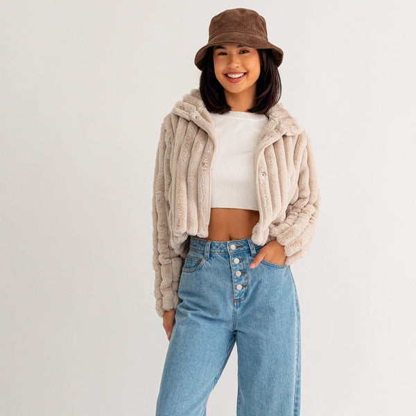 Front view of model wearing jacket. Shows the button closure. Also shows the thick ribbing detail, the crop length, the collar and the fur texture. 