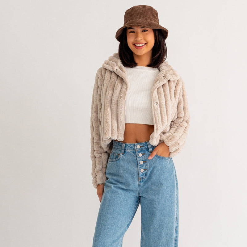 Front view of model wearing jacket. Shows the button closure. Also shows the thick ribbing detail, the crop length, the collar and the fur texture. 