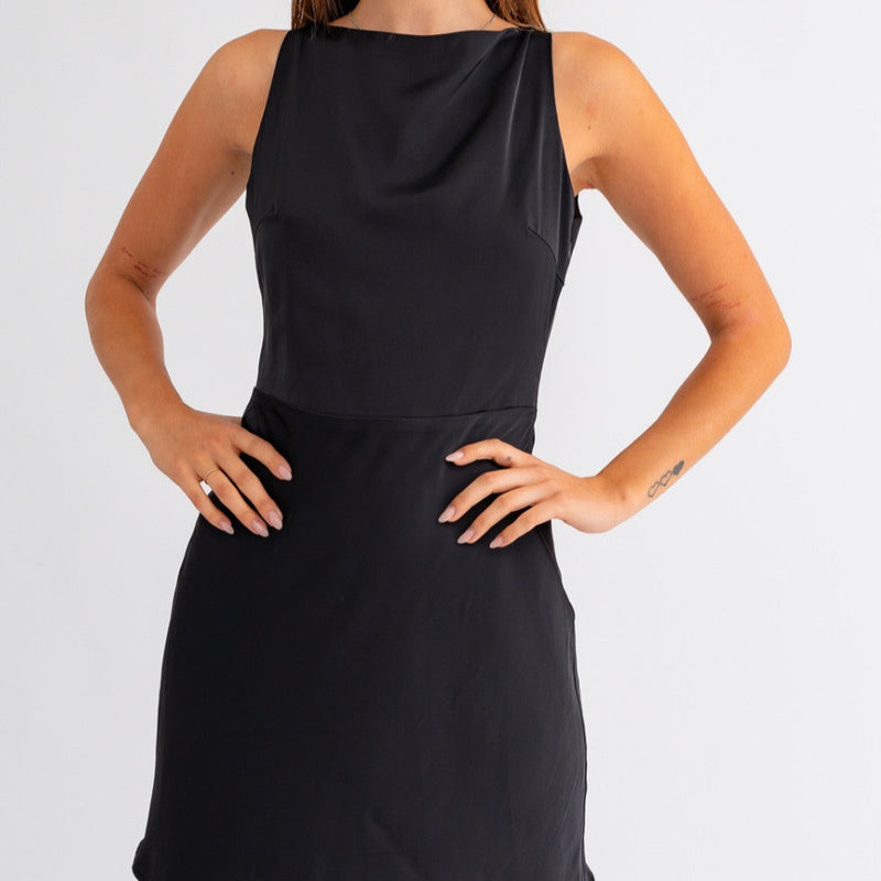 Front view of model wearing dress. Shows the boat neckline. Also shows that dress is sleeveless, the seam through the waist.