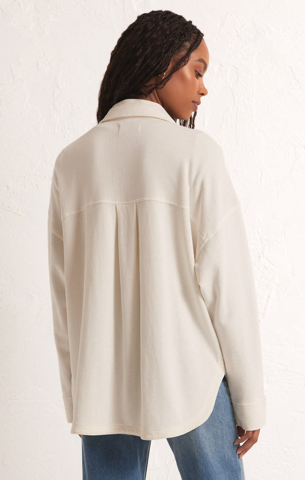 back view of the model wearing the all day knit jacket. shows the pleat on the back. also shows the collar, the dropped shoulders and the bottom curved hem. 