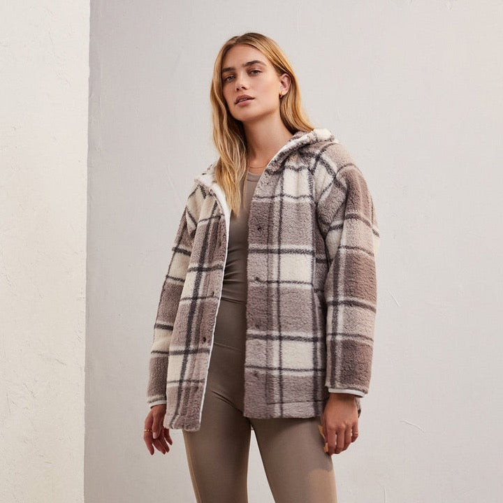 front view of the cross country plaid jacket in lunar grey. shows the snap button closure. also shows the plaid detailing, the drawstring hood, and the front pockets.