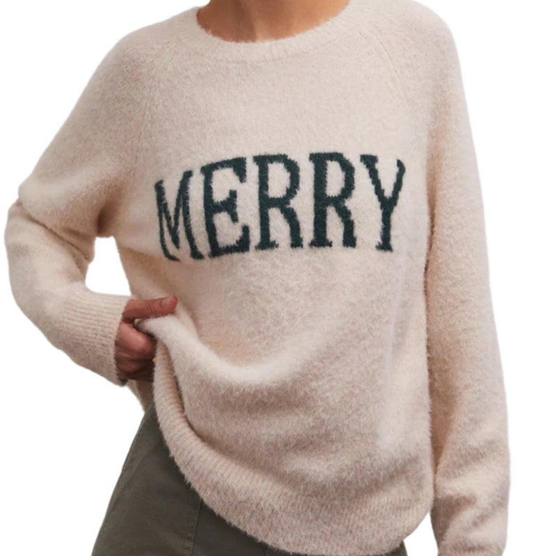 front view of model wearing lizzie merry sweater in light oatmeal heather. shows the wording MERRY on the front. also shows the soft sweater yarns, th relaxed fit, and the ribbed detail on the neckline, cuffs and hem. 