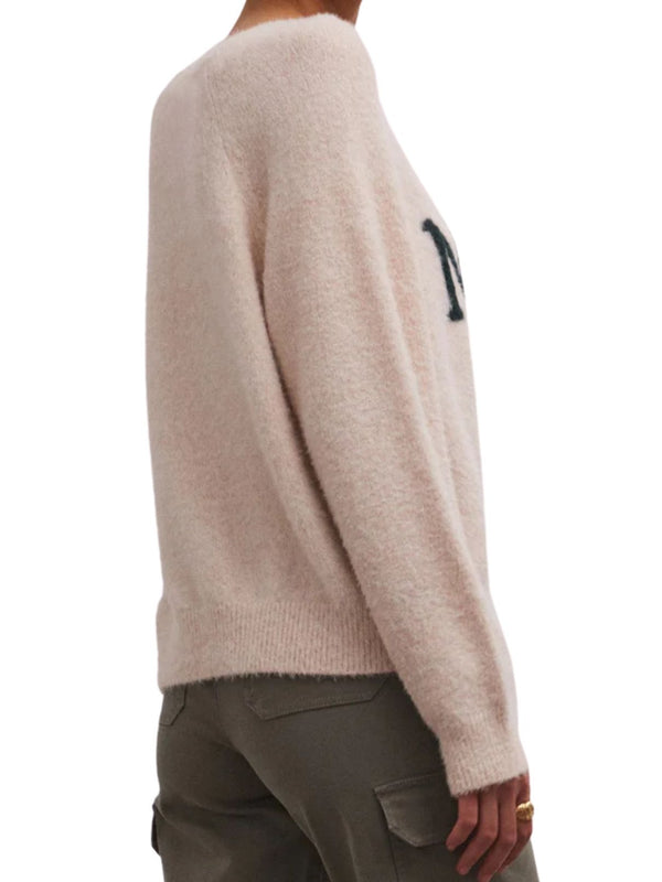 back/side view of model wearing the lizzie merry sweater in light oatmeal heather. shows the ribbed detail on the cuffs and hem. also shows the relaxed fit and the soft sweater yarns. 