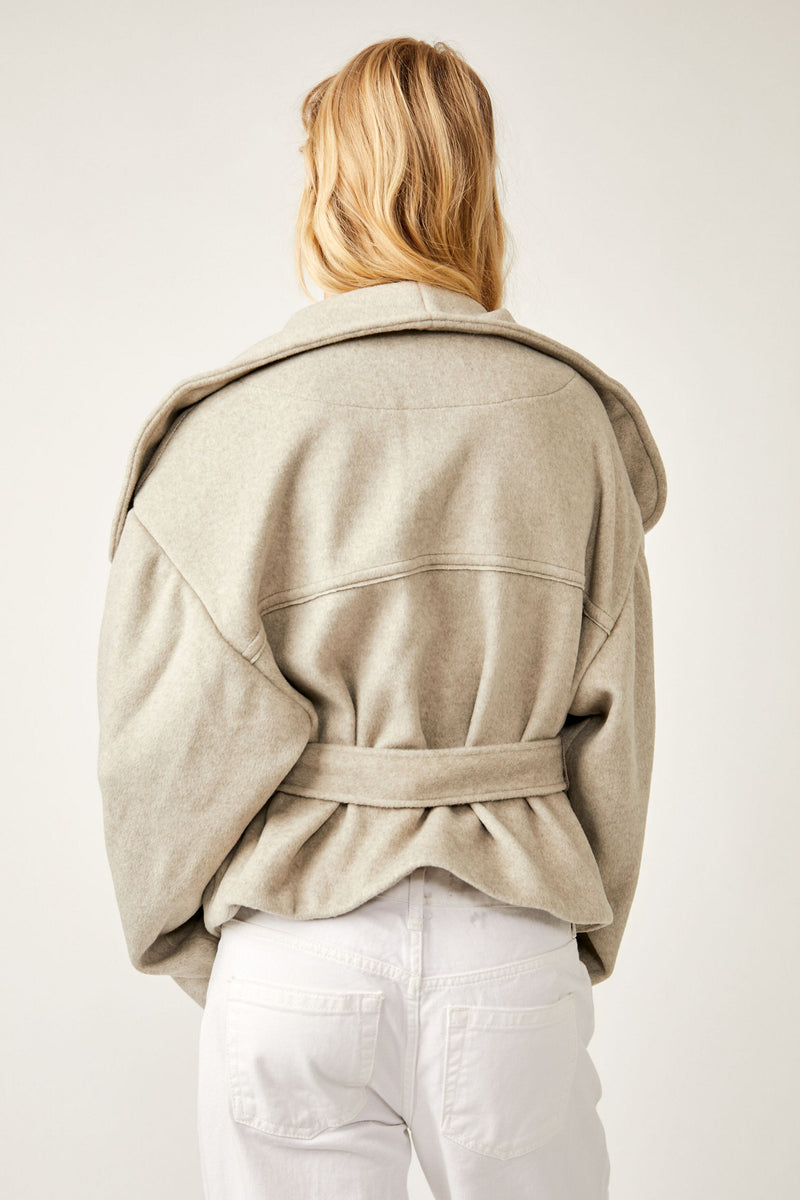 Back view of model wearing jacket. Shows the back tie waist detail and the exaggerated collar. 