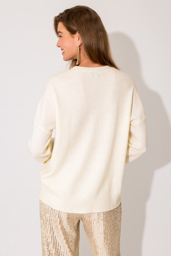 Back view of model wearing sweater. Shows the crew neckline. Also shows the drop shoulders seams, the ribbed detailing on the neckline and bottom hem, and the beautiful color white. 