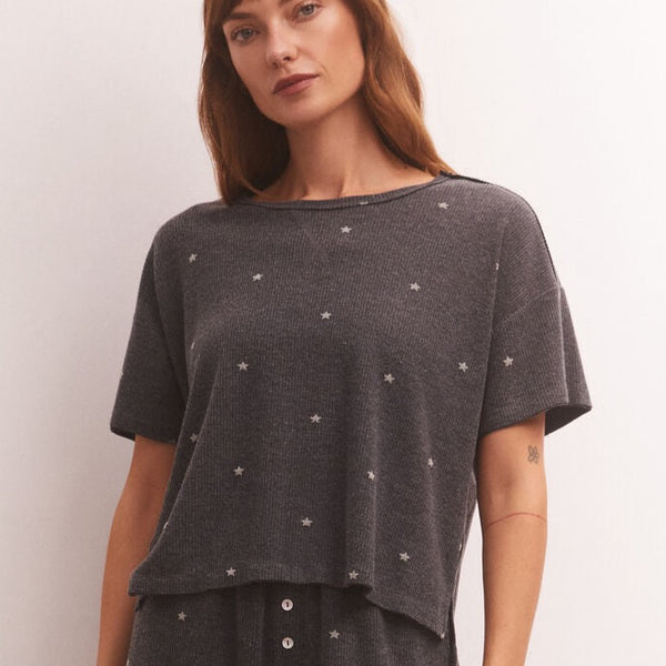 front view of model in shirt. shows the relaxed crew neckline, dropped shoulders, short sleeves, boxy fit and mini star print all over.