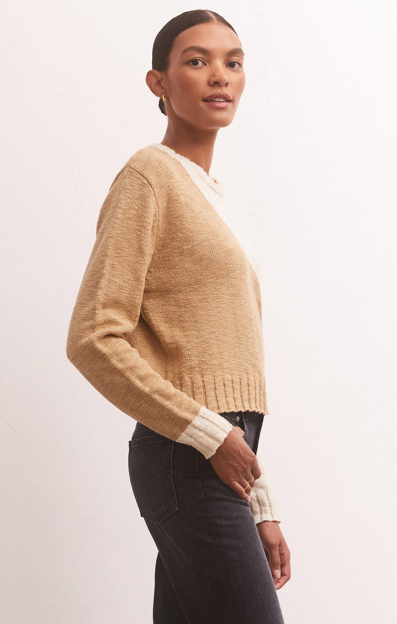 side view of model in sweater. shows the cropped length, and contrast ribbed hemline.