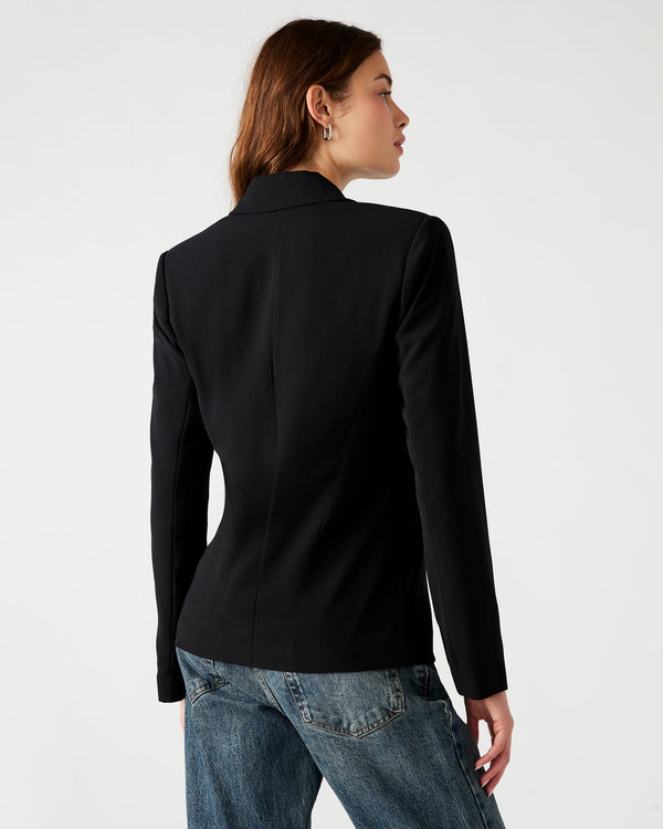 Back view of model wearing blazer. Shows the back of the collar. Also shows the defined seam down the middle of the back, the length of the jacket is little longer and the color of the blazer is black. 