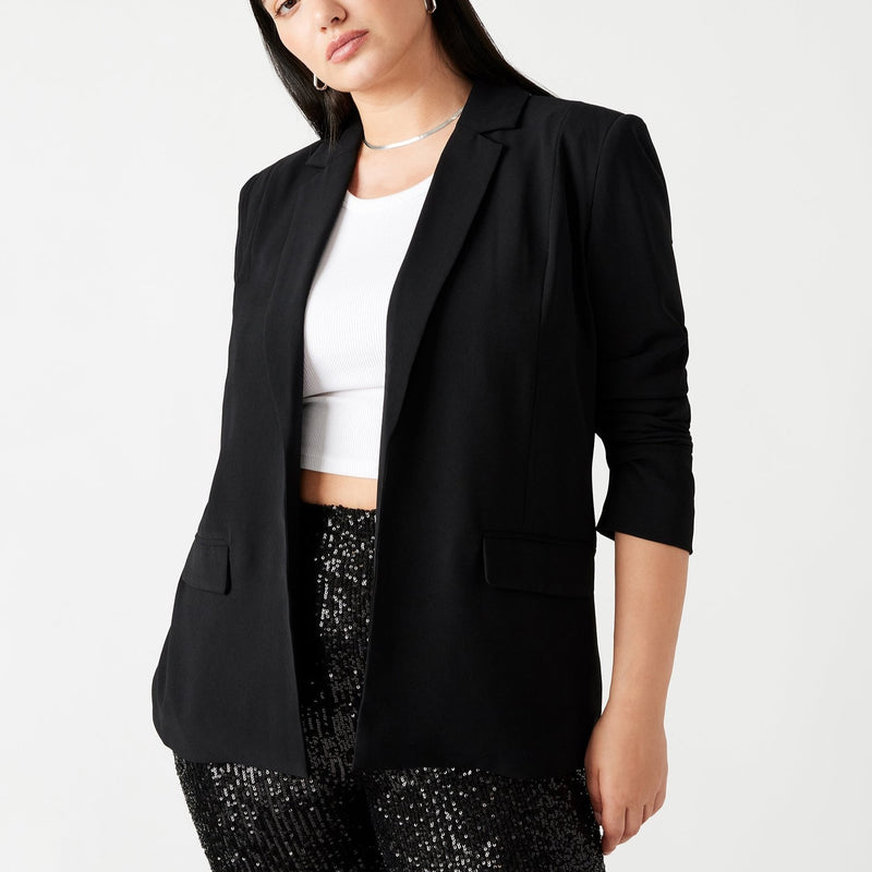 Front view of model wearing blazer. Shows the open front. Also shows the tailored collar, the two front flap pockets and the color of the blazer is black. 