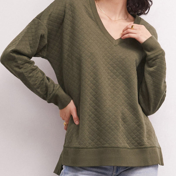 Front view of model wearing the weekender. Shows the V-neckline. Also shows the quilted detail and the step hems and the side vent details in this beautful kelp color.  