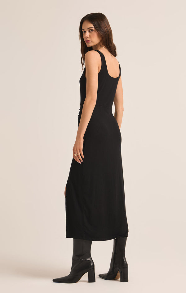 back/side view of the model wearing the melbourne dress. shows the back scoop neckline. also shows the fitted bodice and the long maxi length. 