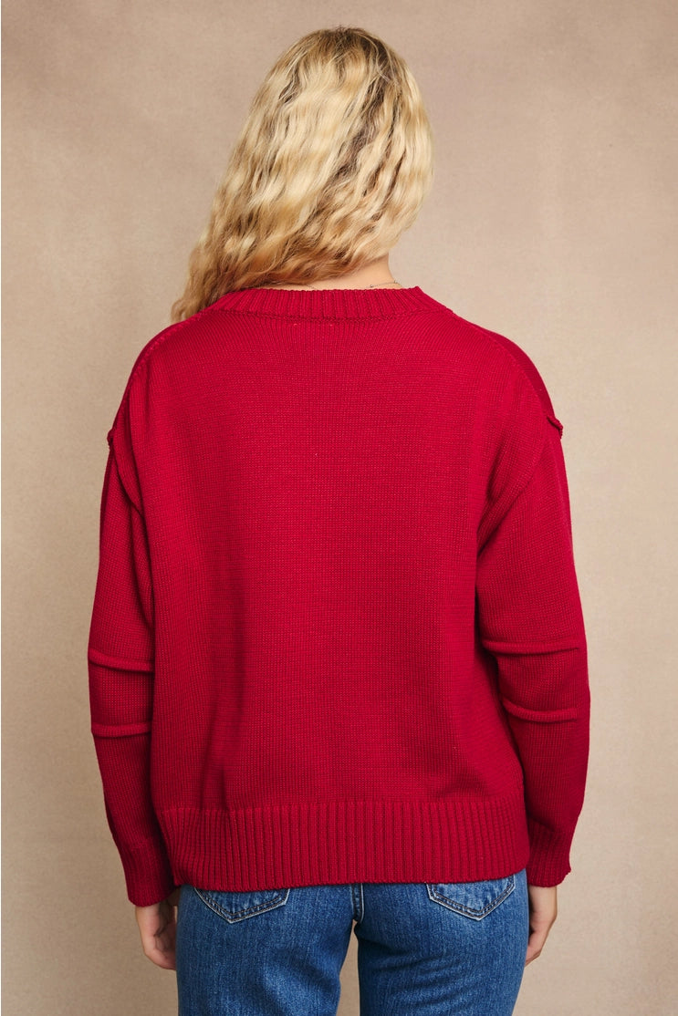 back view of the rosy sweater top. shows the pleated sleeves. also shows the red color, the ribbed detailing, the dropped shoulders and the longer back. 