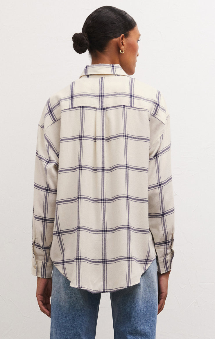 Back view of model wearing button up. Shows the shirttail bottom hem, Also shows the button closure cuffs, the collared neckline and the relaxed fit. 