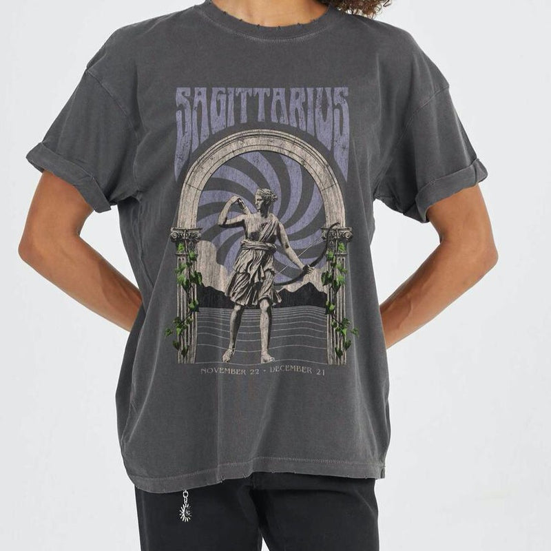 Front view of model wearing tee. Shows the crew neckline. Also shows the cuff sleeves, distressing on neckline and the sagittarius zodiac graphic. 
