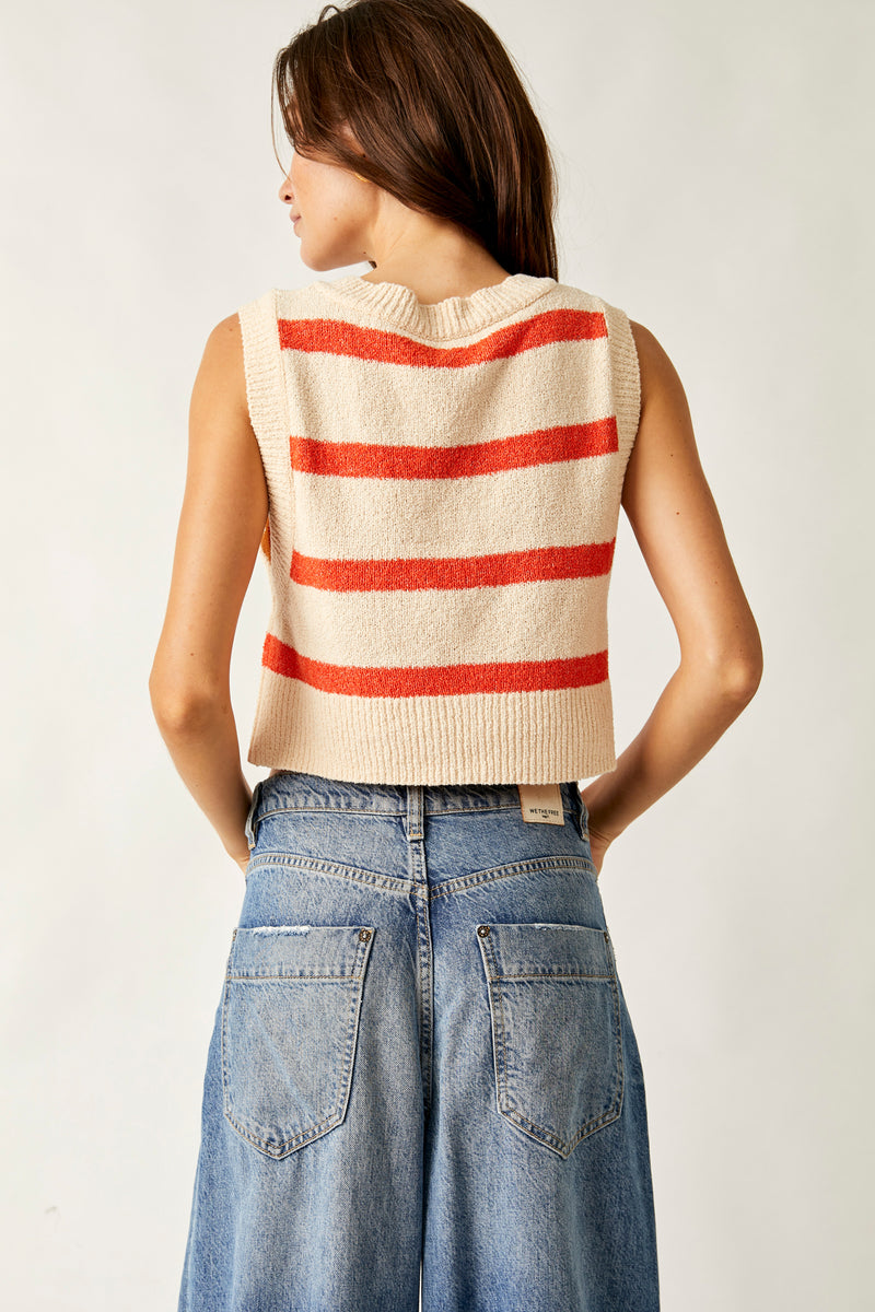 back view of the model wearing the Santa Monica vest in this cream color with orange stripes. shows the crop length of the vest. also shows that the back is alittle longer than the front, the ribbed detail on the hem , neckline and the sleeves, 