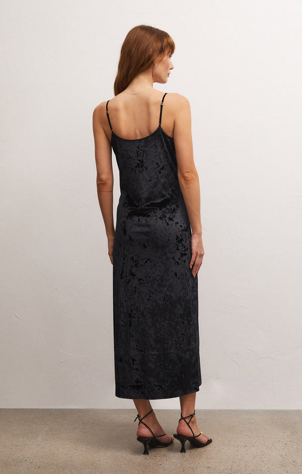 back view of the Selina velvet dress. shows the adjustable spaghetti straps. also shows the midi length and the velvet fabric. 
