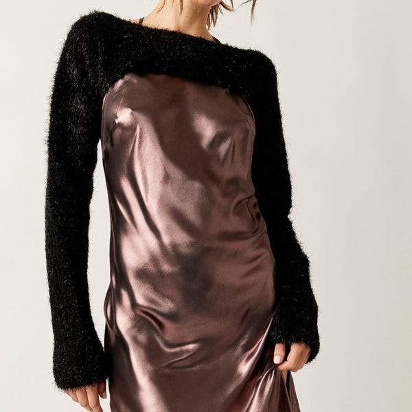 front view of model wearing the shimmer bolero in black. shows the wide neck. also shows the ultra cropped length, the exaggerated sleeves and the metallic accents throughout. 