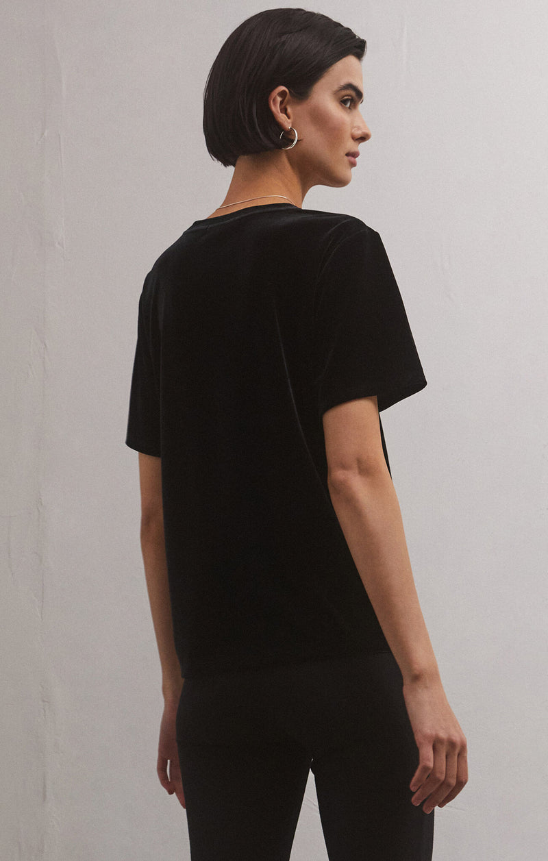 back/side view of model wearing the Simone velvet top in black. shows the velvet detail. also shows the shorts sleeves and the crew neckline. 