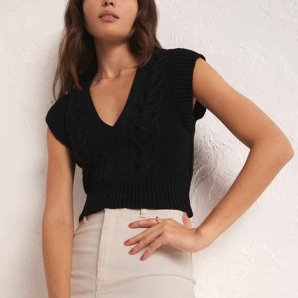 front view of model wearing the roped in sweater vest. shows the  deep v neckline. also shows the fitted style, the crop length of the vest and that its sits above the waist. 