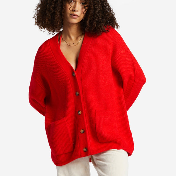 Front view of model wearing sweater. Shows the v neck. Also shows the front pockets, the button down closure and this rad red color. 