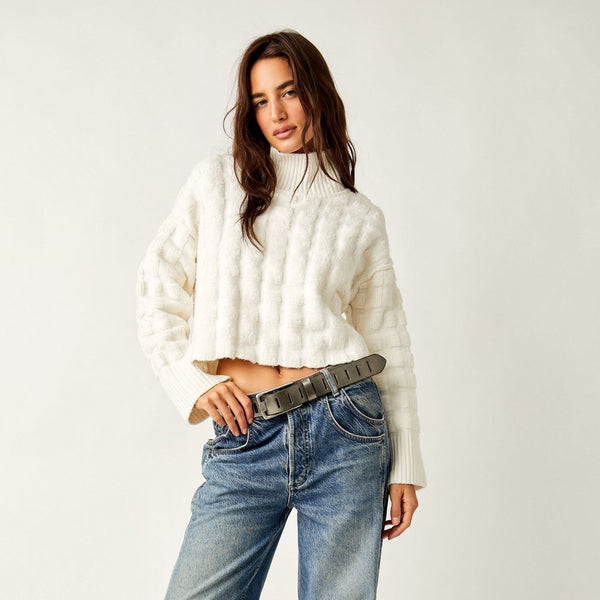 front view of model wearing the soul searcher mock neck sweater in ivory. shows the ribbed hems. also shows the defined neckline, the cropped style, the puffer look detail throughout sweater.