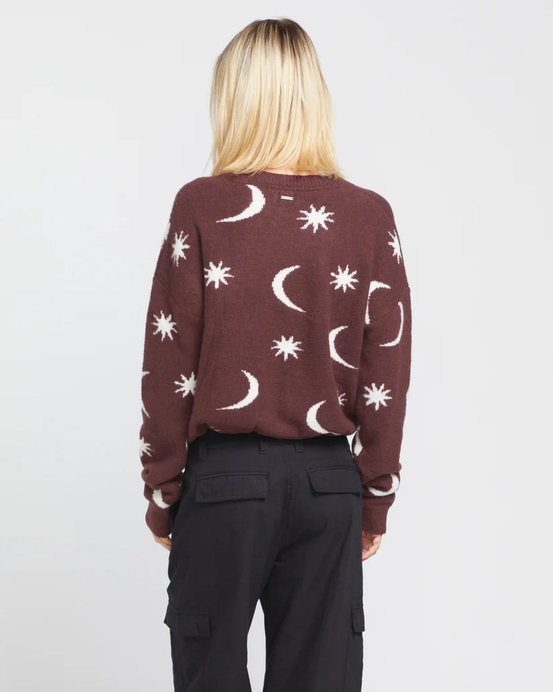 back view of the model wearing the nyte tone sweater. shows the moon and stars pattern. also shows the elastic waist and the dropped shoulders.