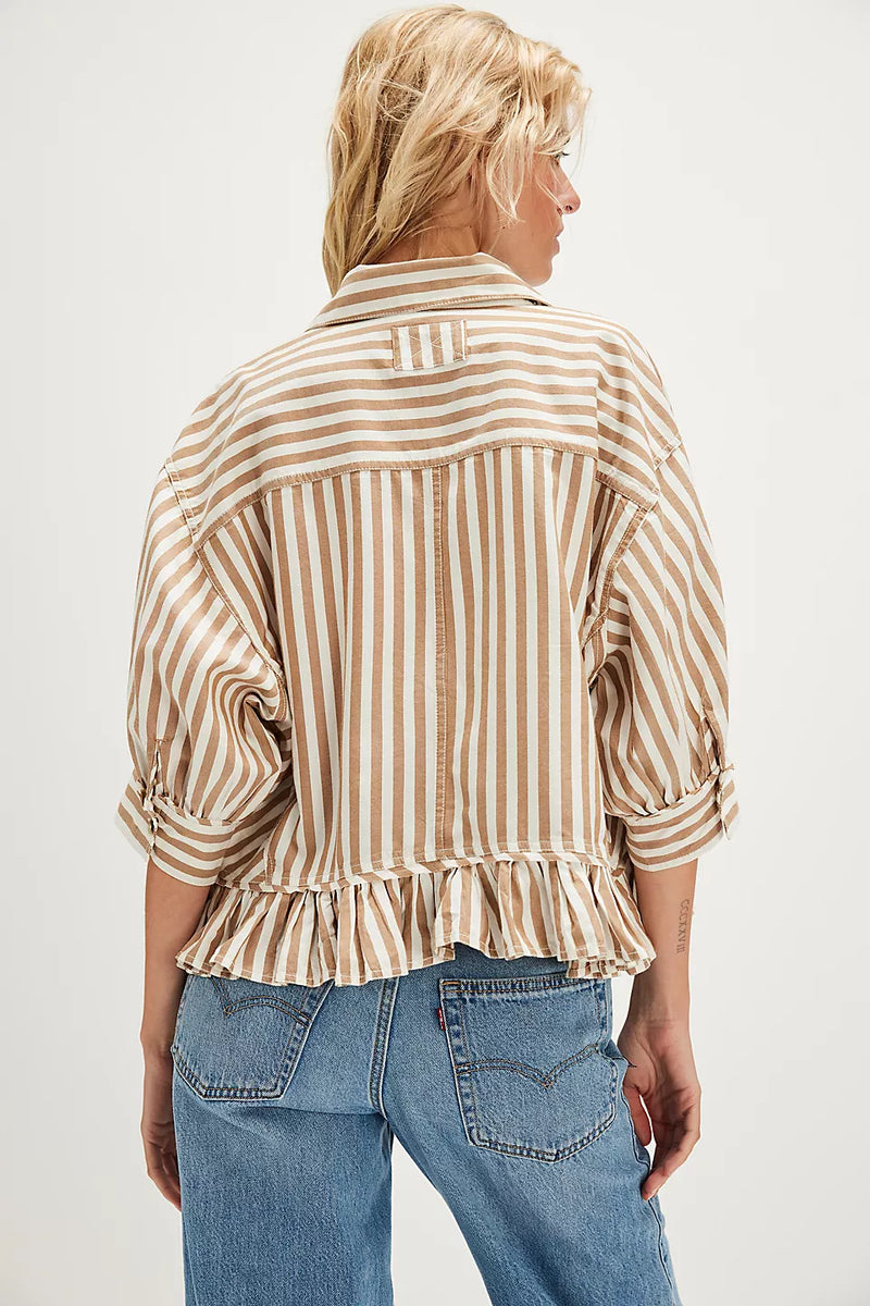 back view of the model wearing the bailey striped shirt. shows the dropped shoulders. also shows the ruffle hem, the 3/4 sleeves, the colored neckline and the tan and white stripes. 