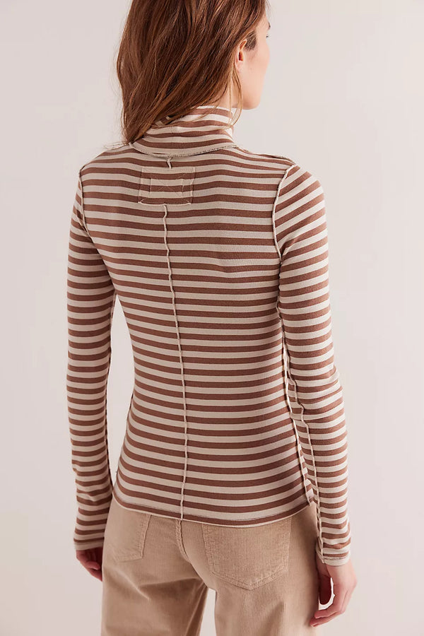 Woman wearing a brown and beige striped long-sleeve top against a plain background