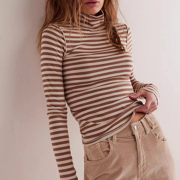 Woman wearing a striped turtleneck and beige pants against a plain background
